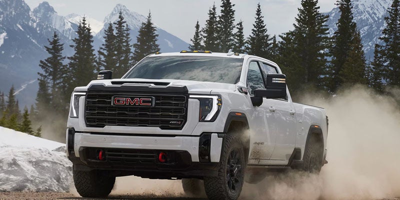 White GMC Sierra 2500HD Performance truck driving near HEREFORD, TX through rugged mountain terrain.
